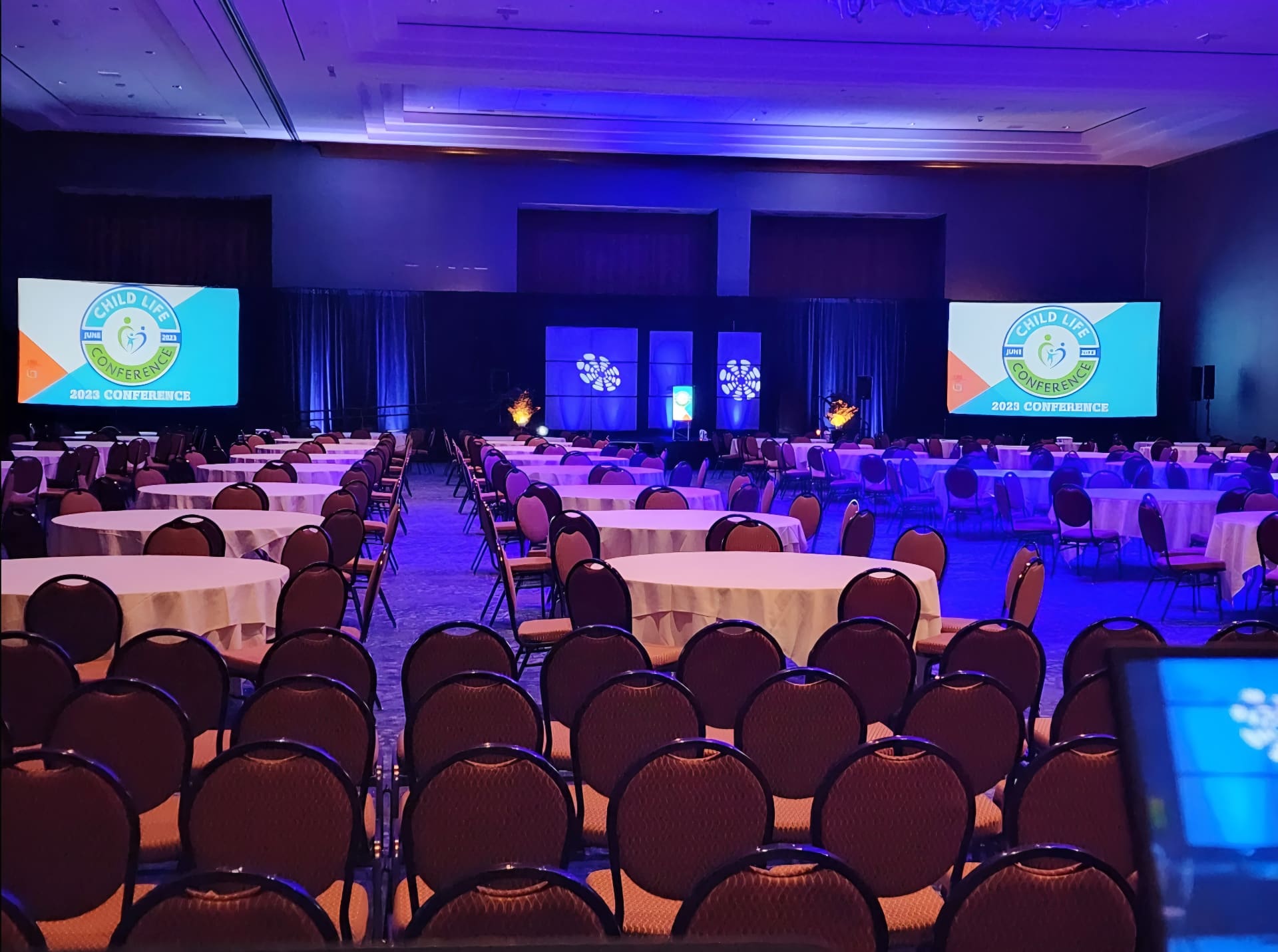Large conference hall with dual branded screens and stage lighting